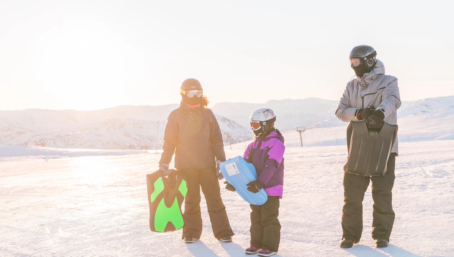 Family of three carrying their sleds, photo