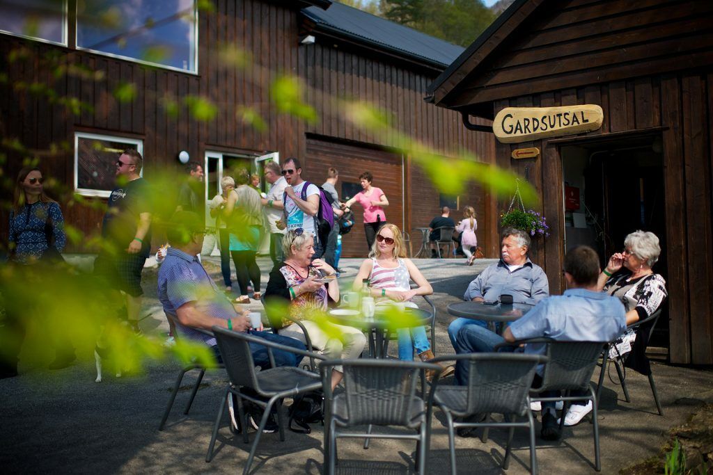 Gruppe sitzt an einem sonnigen Tag vor dem Hofladen in Ulvik.