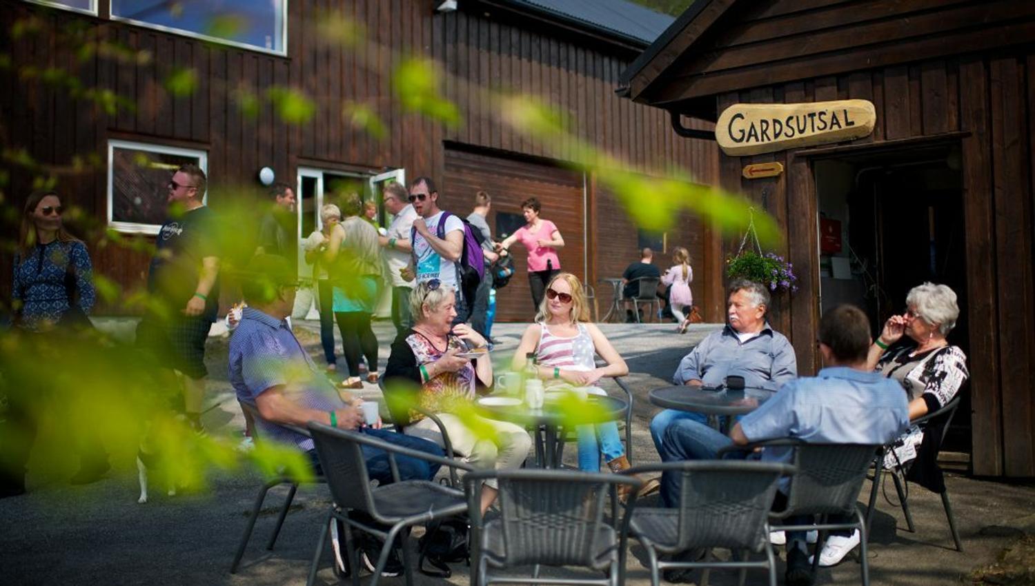 Gruppe sitzt an einem sonnigen Tag vor dem Hofladen in Ulvik.