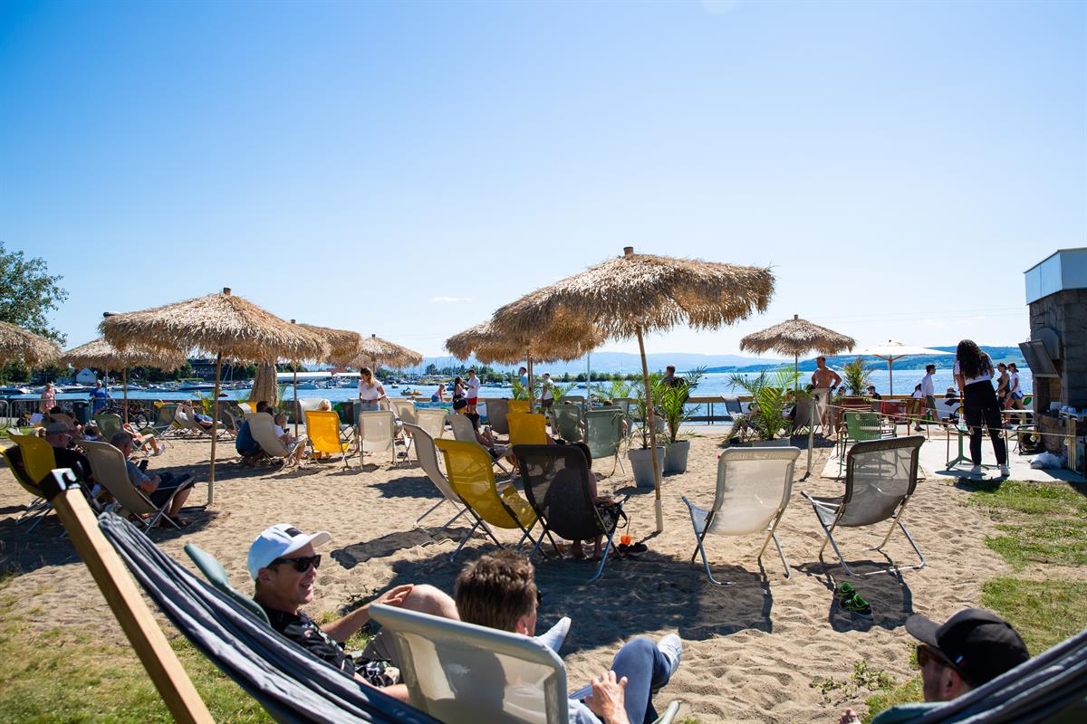 Solfylt strandområde med solsenger, parasoller og gjester som slapper av.