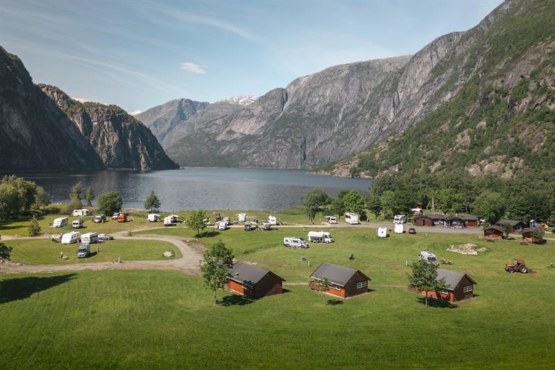 Sæbø camping sett fra hovedveien, med vann og fjell i bakgrunnen.