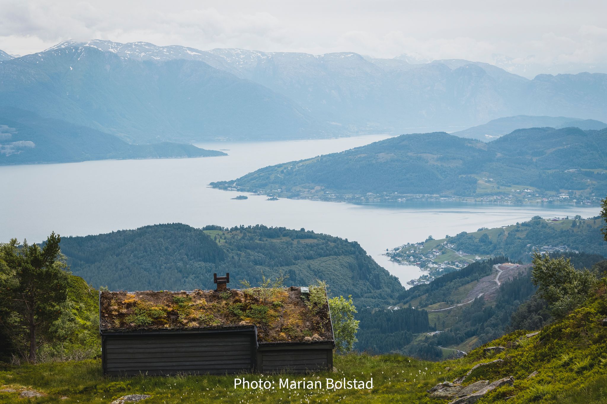 View over fjord and cultural landscape in Hardanger, Norway, with traditional mountain cabin
