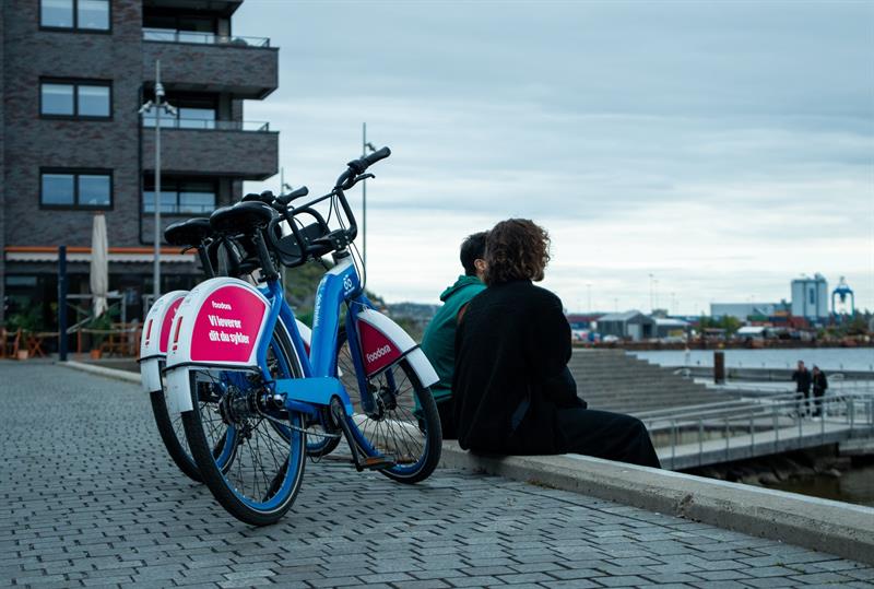 To personer som sitter på en bryggekant, med to bysykler bak dem