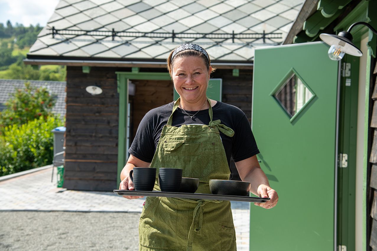 Hostess at Eldhuset Farm Restaurant serving guests with a smile in Hardanger.