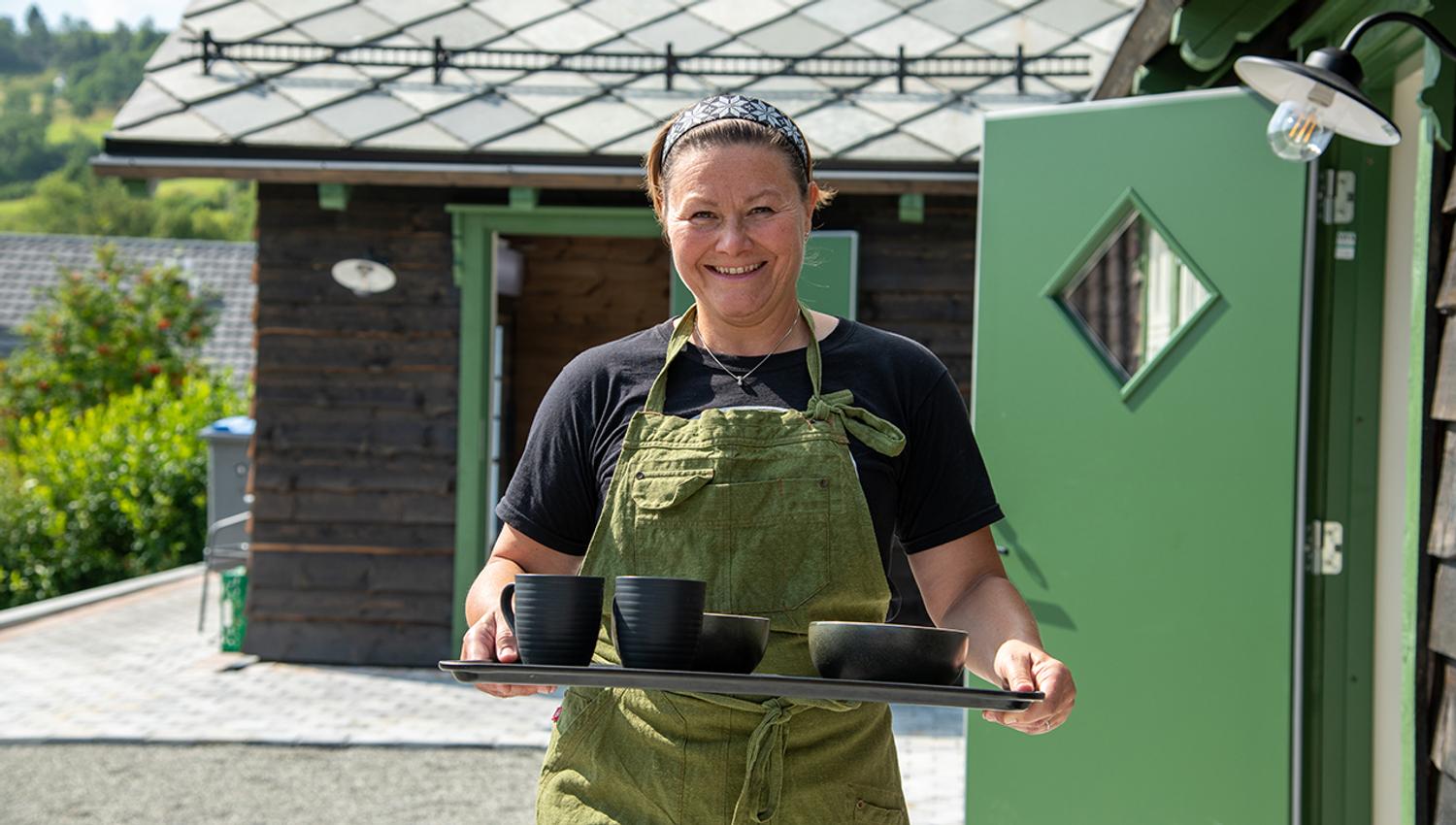 Hostess at Eldhuset Farm Restaurant serving guests with a smile in Hardanger.