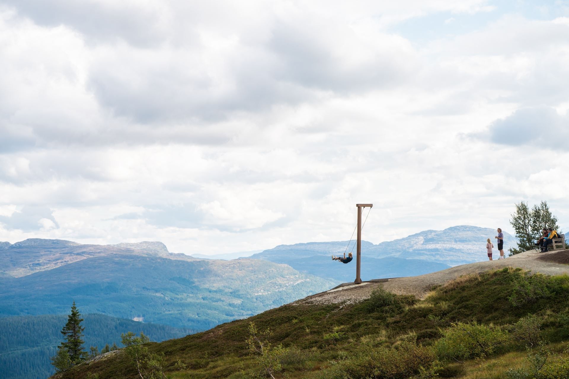 En gutt husker på hangurshusko, sett fra siden. I bakgrunnen ser du fjellene. 
