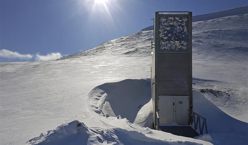 Inngangspartiet til Svalbard Globale Frøhvelv i lyse snødekte omgivelser med solskinn og blå himmel i bakgrunnen