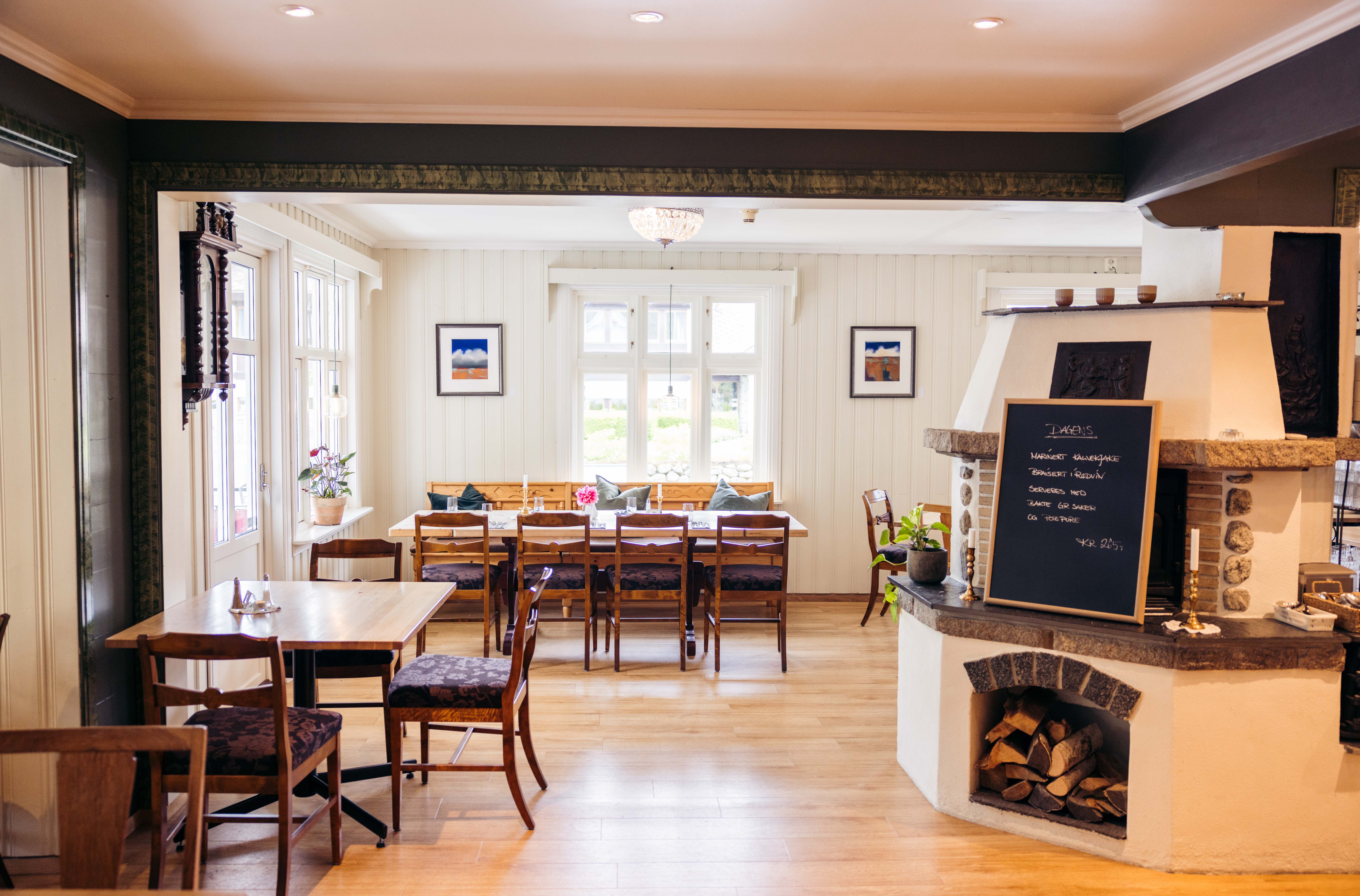 A photo of the restaurant, showing several dining tables and a fireplace.