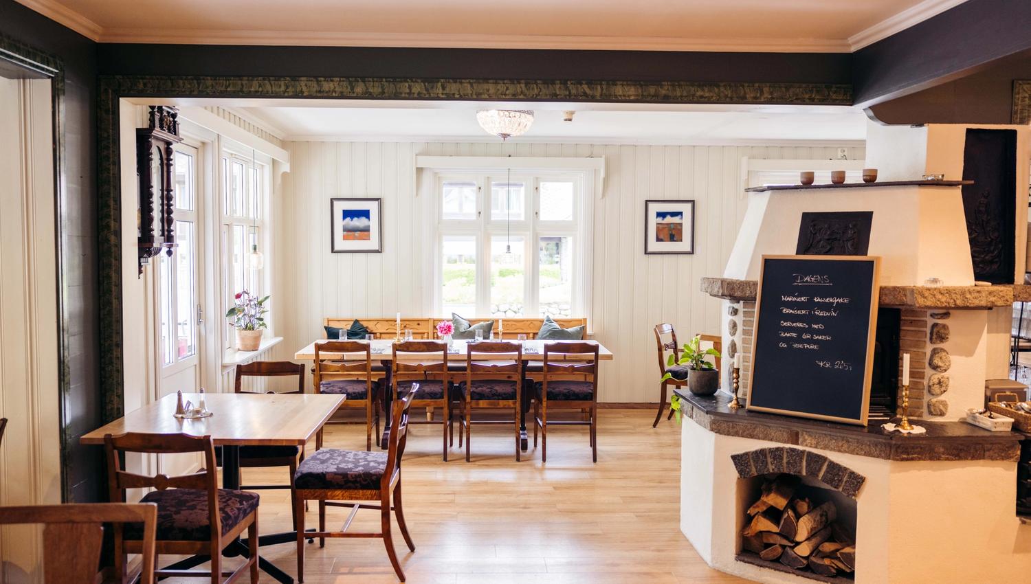 A photo of the restaurant, showing several dining tables and a fireplace.