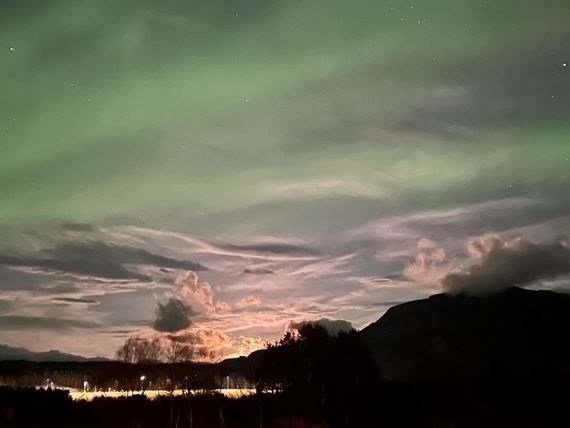 Northern Lights above the mountains and thin, contrasting clouds