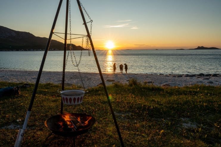 Bonfire on the beach with guests watching the sunset