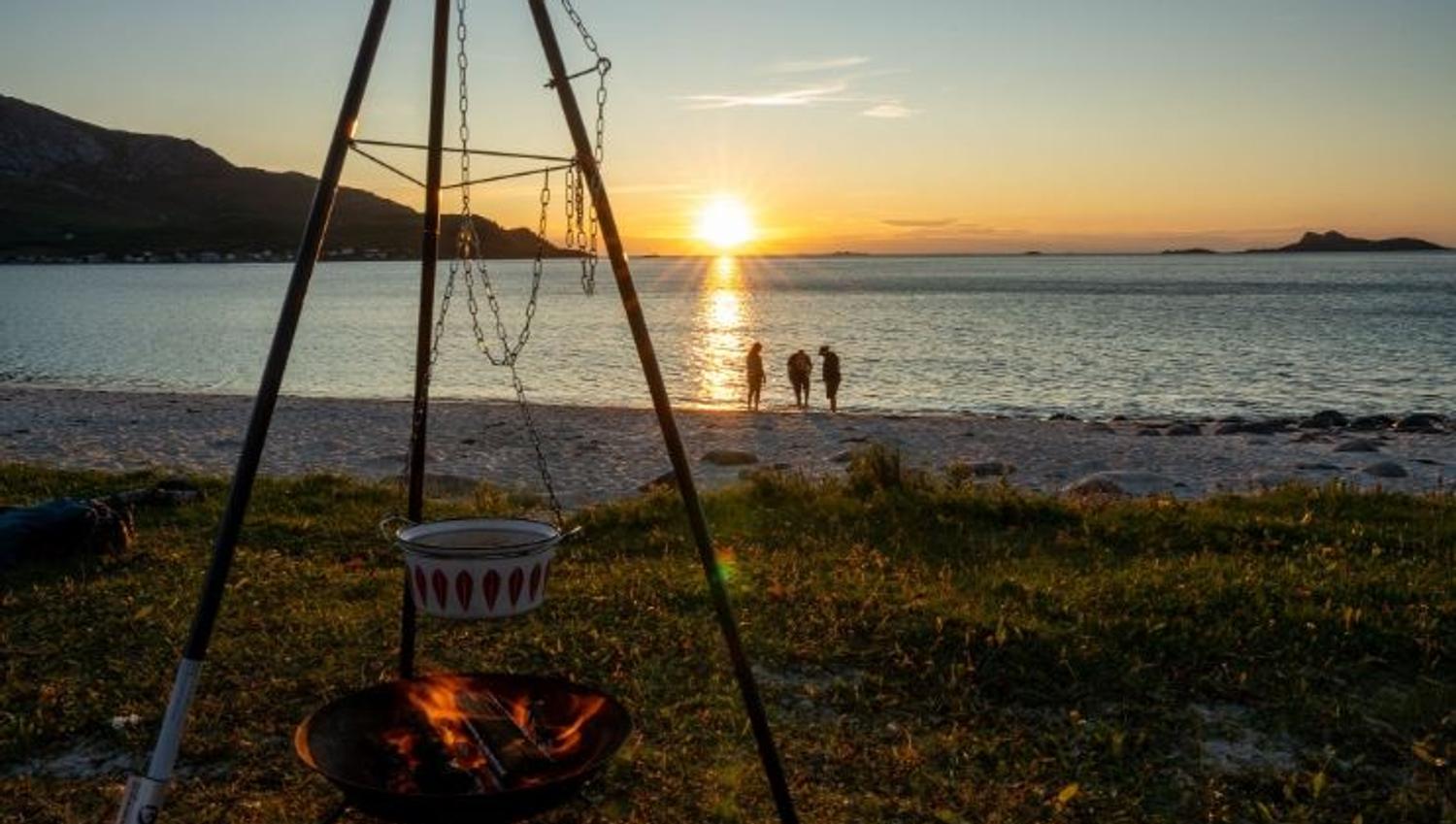 Bonfire on the beach with guests watching the sunset
