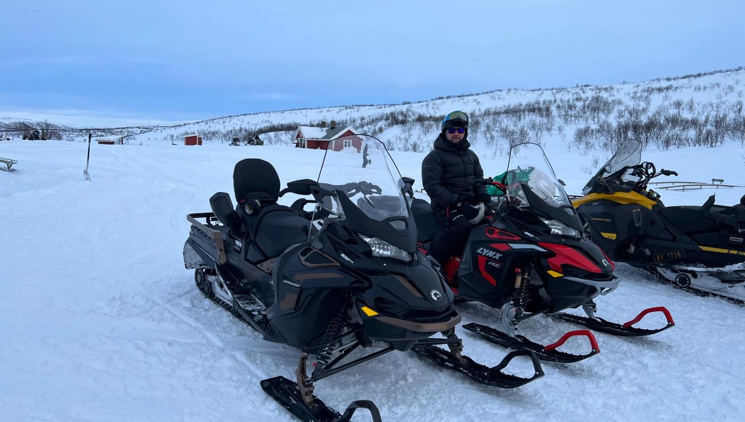 Sneeuwscooters in de sneeuw met een persoon die op een scooter zit.