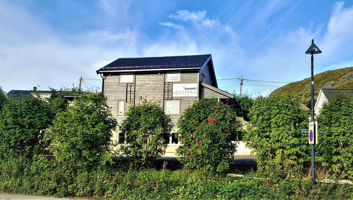 The guest house behind some green trees