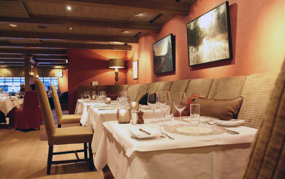 Interior with seating section, set tables with white cloth, chairs and pink walls.