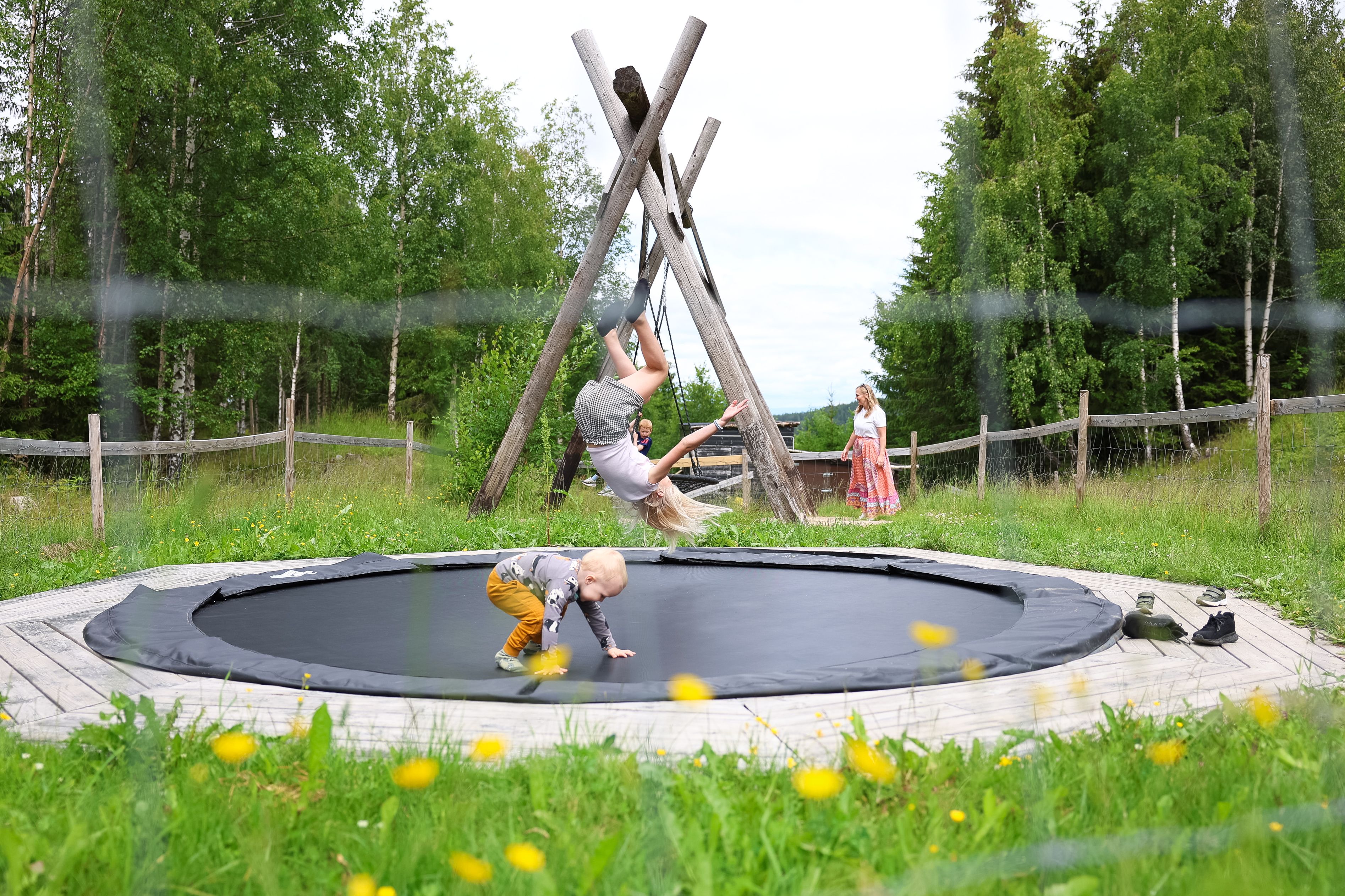 Barn som går over en trebro omgitt av grønne trær i naturparken