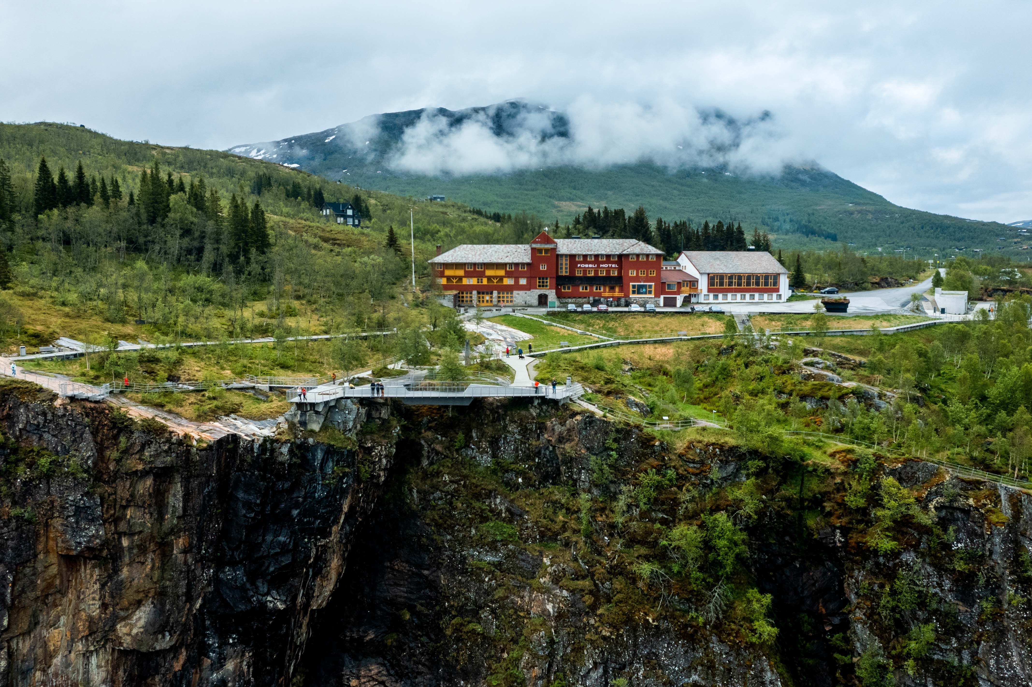 A drone shot of the Fossli Hotel sitting above the waterfall.
