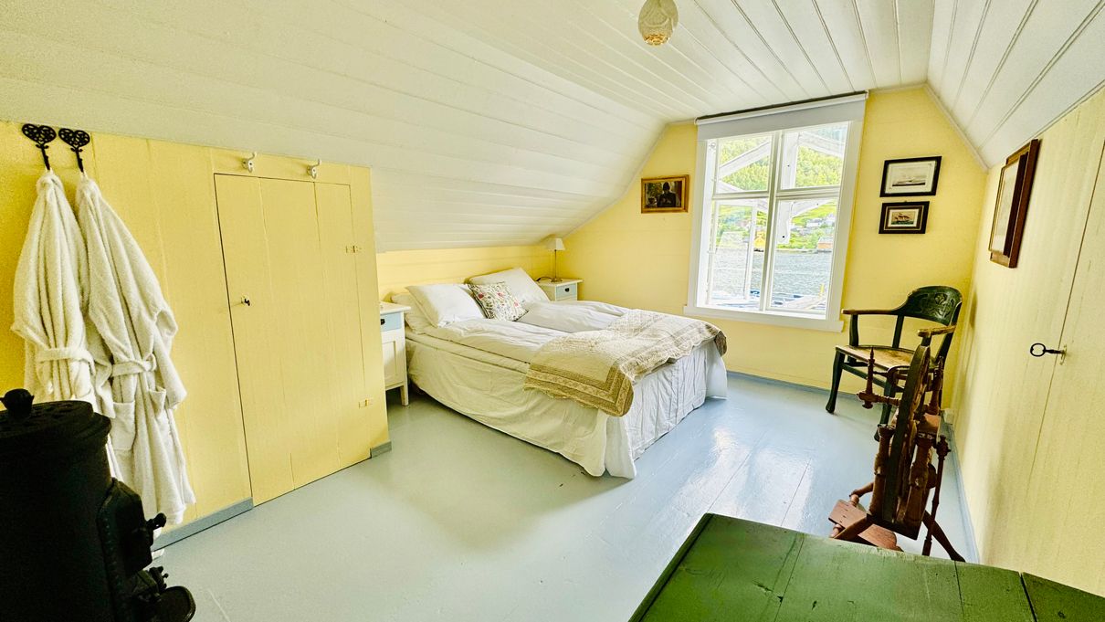 The Yellow Room at Kramsjø Guesthouse – warm and inviting with a view of the fjord and green hills.