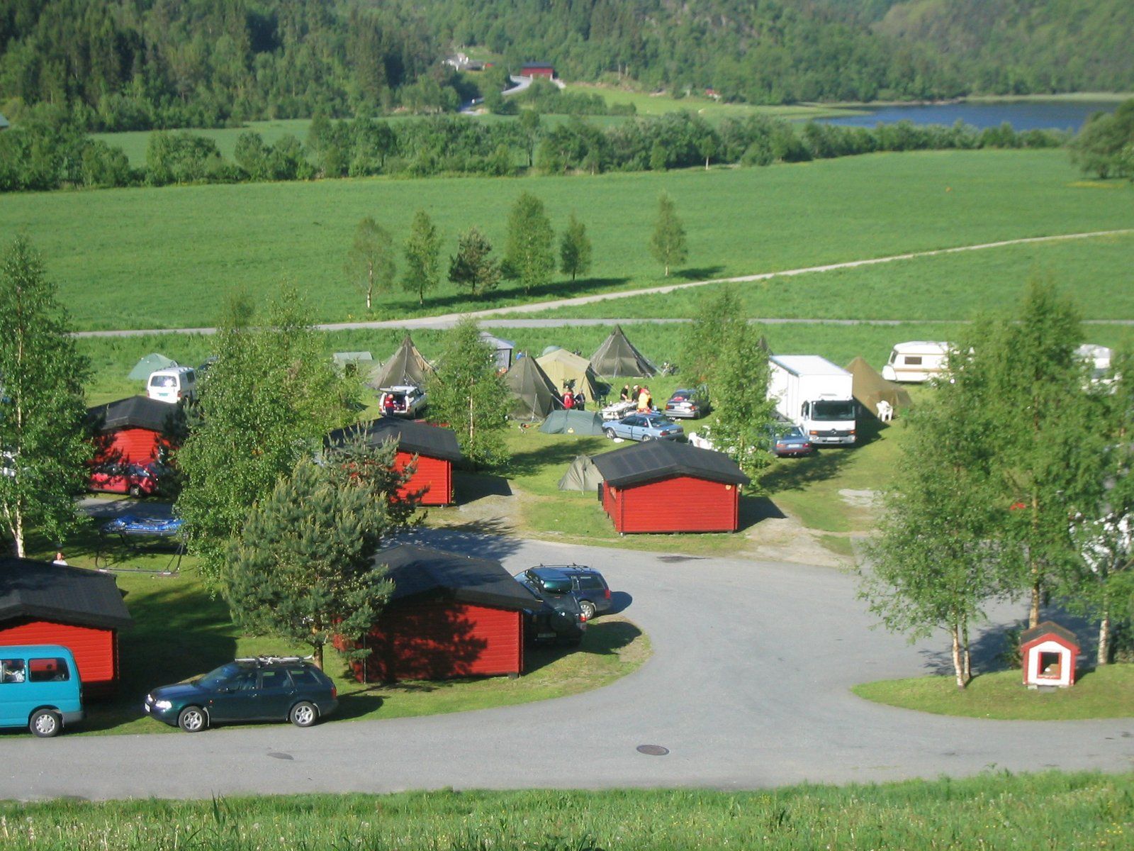 The campsite at Folgefonn Cabins and Farm Camping surrounded by nature, tents, and cabins overlooking the water.