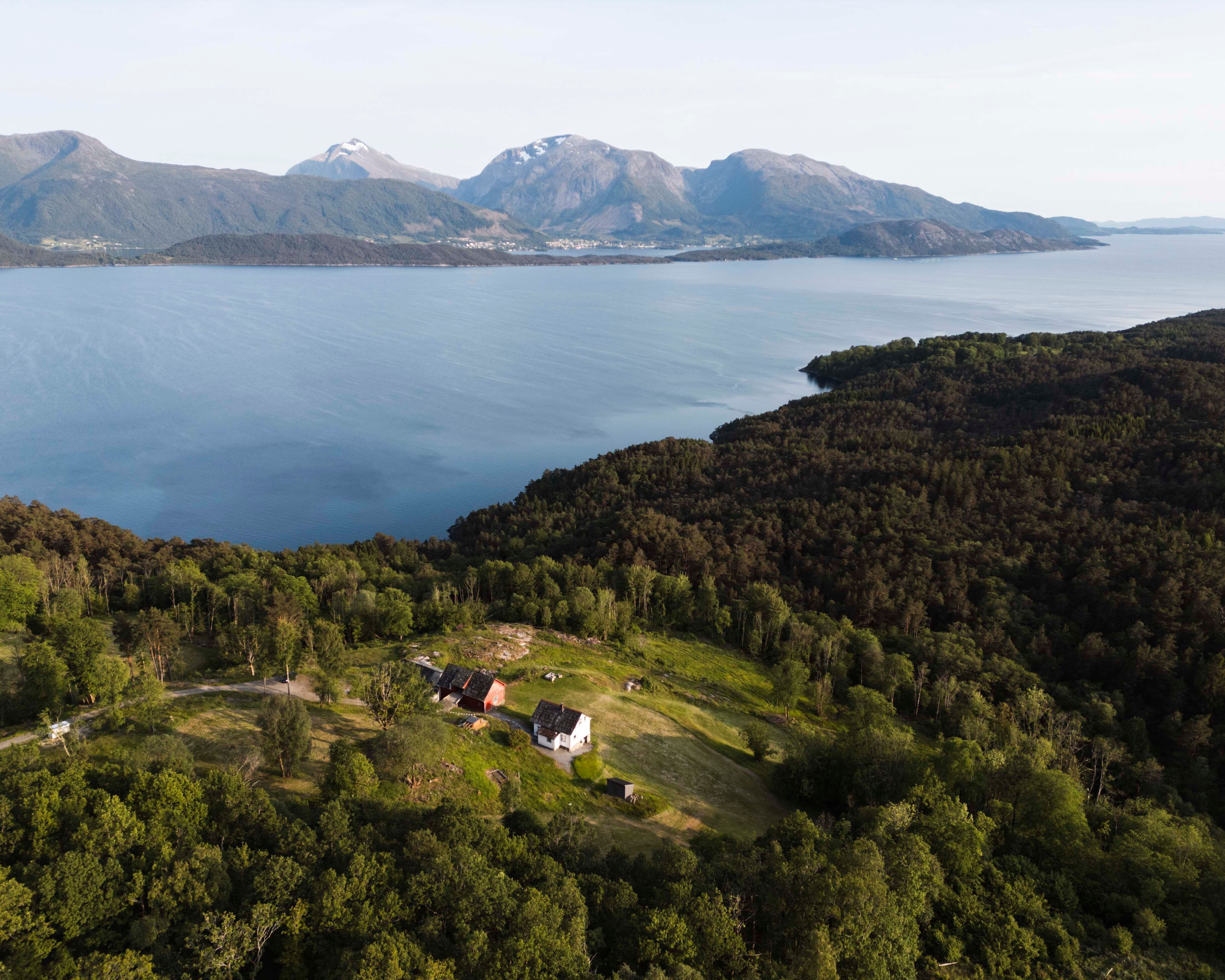Aerial view of Stigen Fjordlodge surrounded by mountains, forest and the Hardangerfjord.