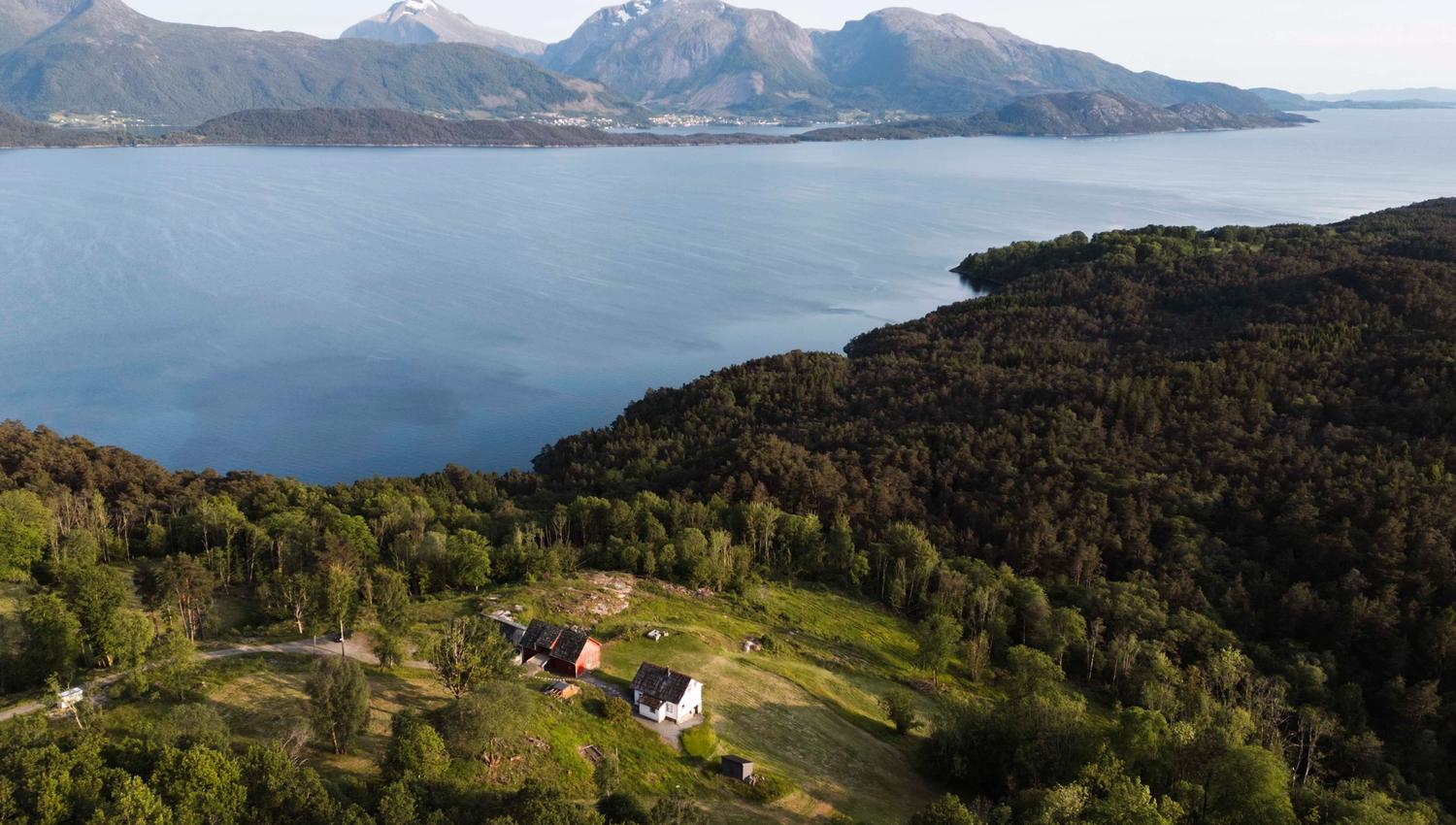 Aerial view of Stigen Fjordlodge surrounded by mountains, forest and the Hardangerfjord.
