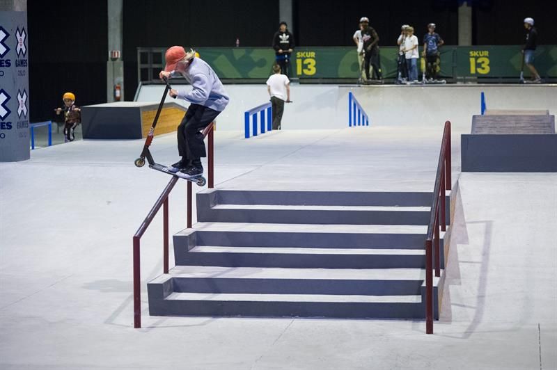 person doing tricks with a scooter on a ramp 