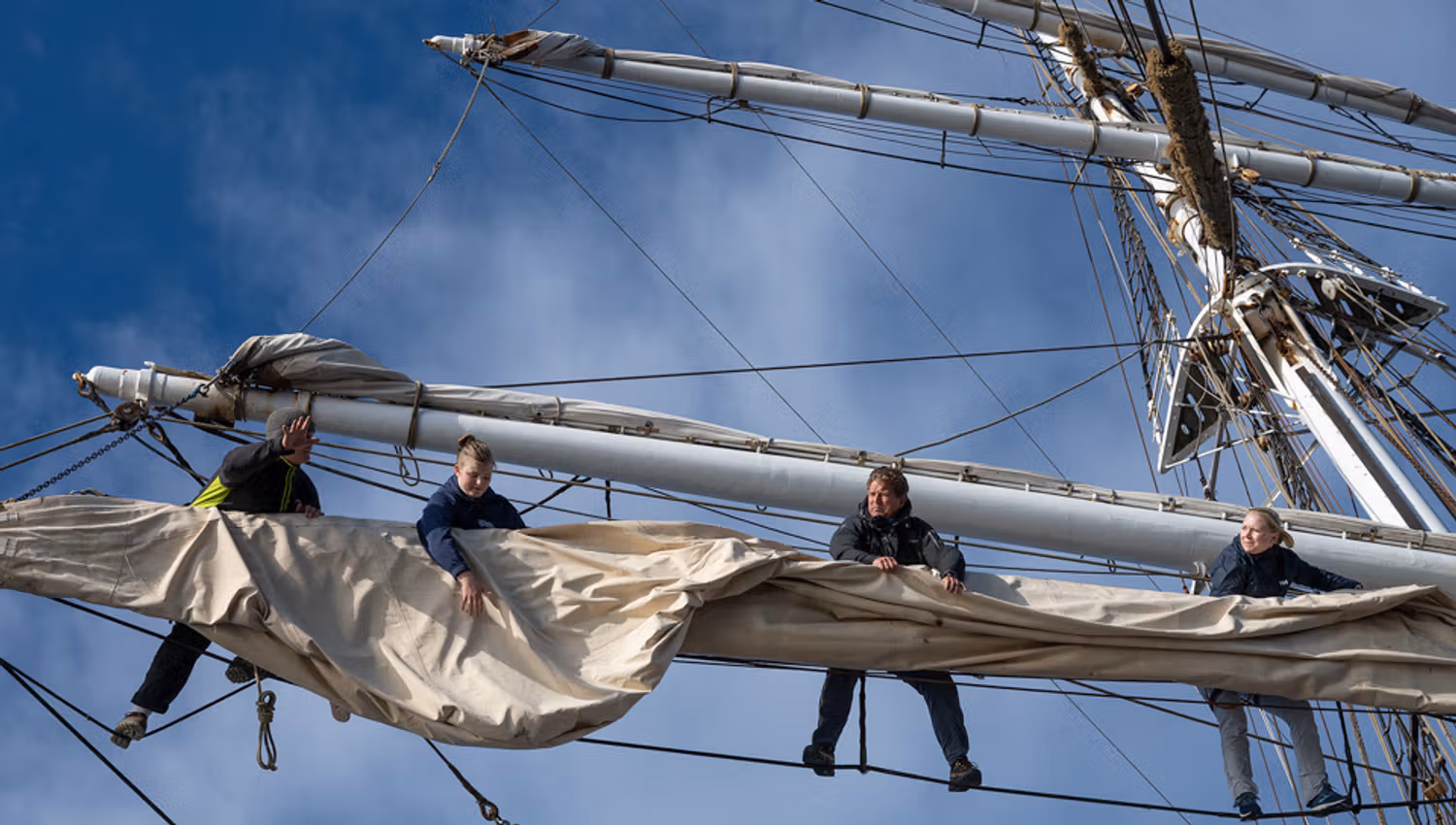 People hanging from the mast.