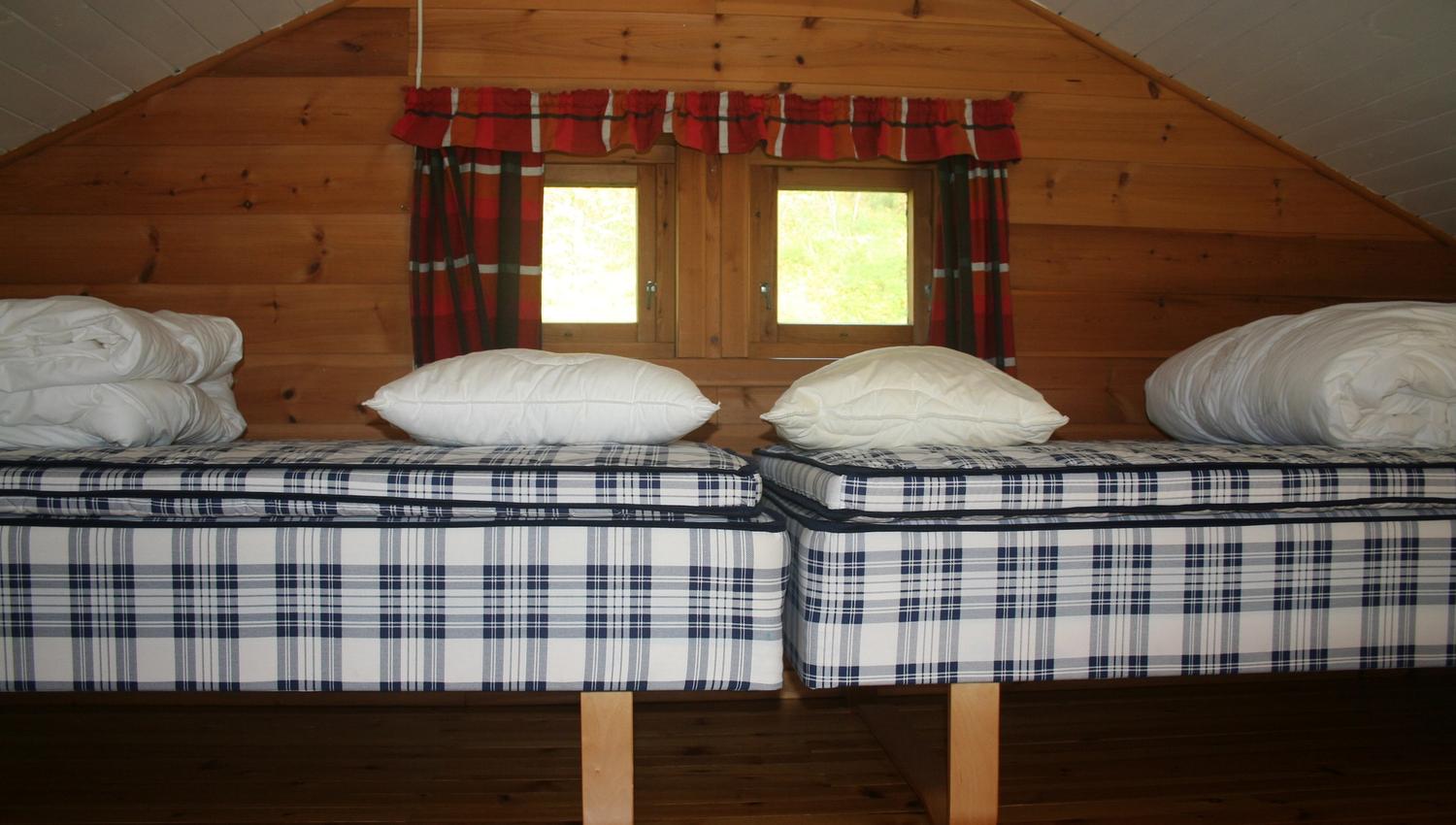 Cozy loft area with two comfortable single beds and a charming window view.