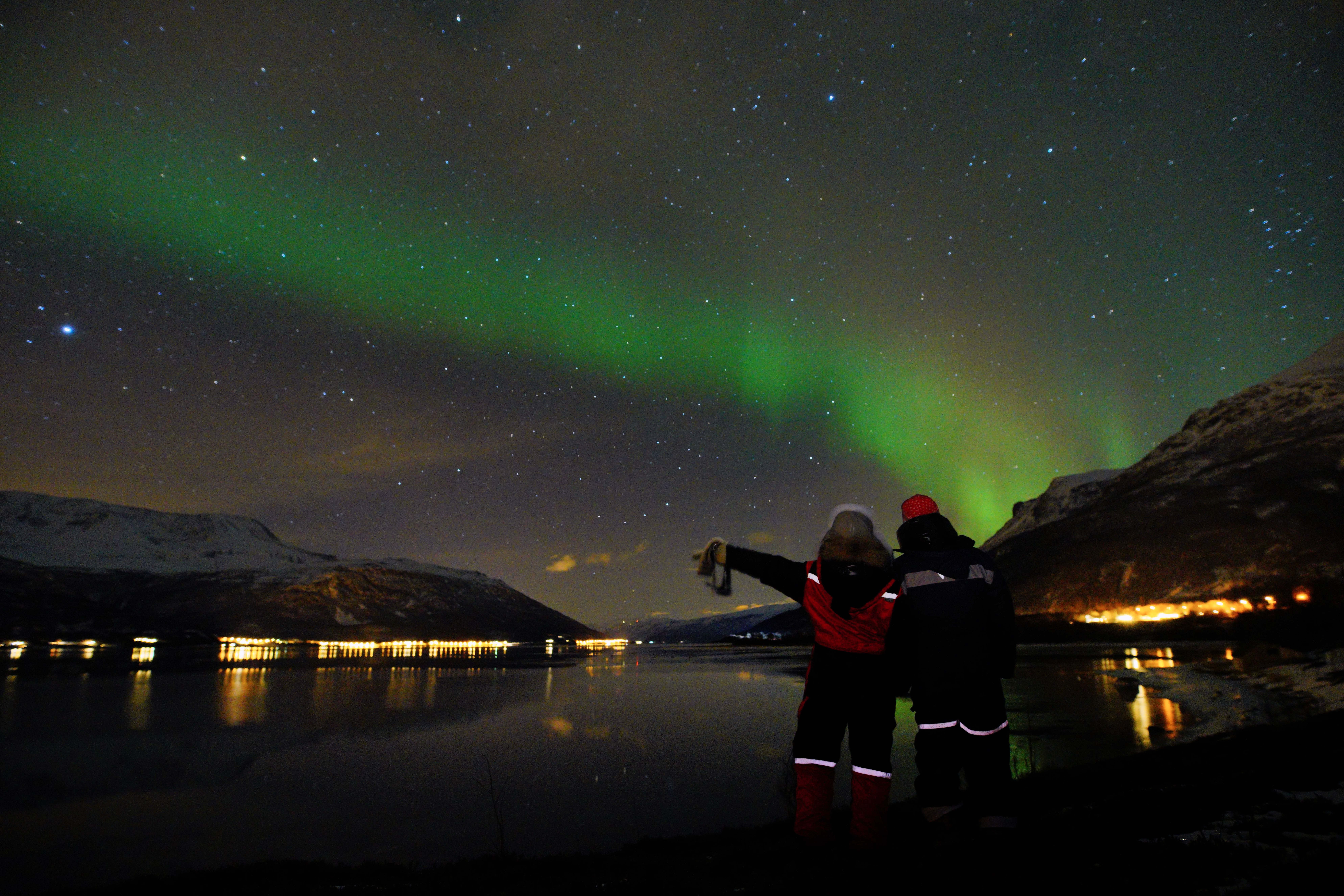 to personer som nyter nordlyset over fjorden