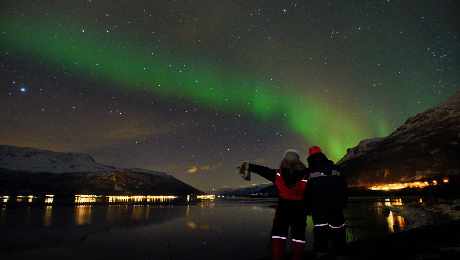 to personer som nyter nordlyset over fjorden