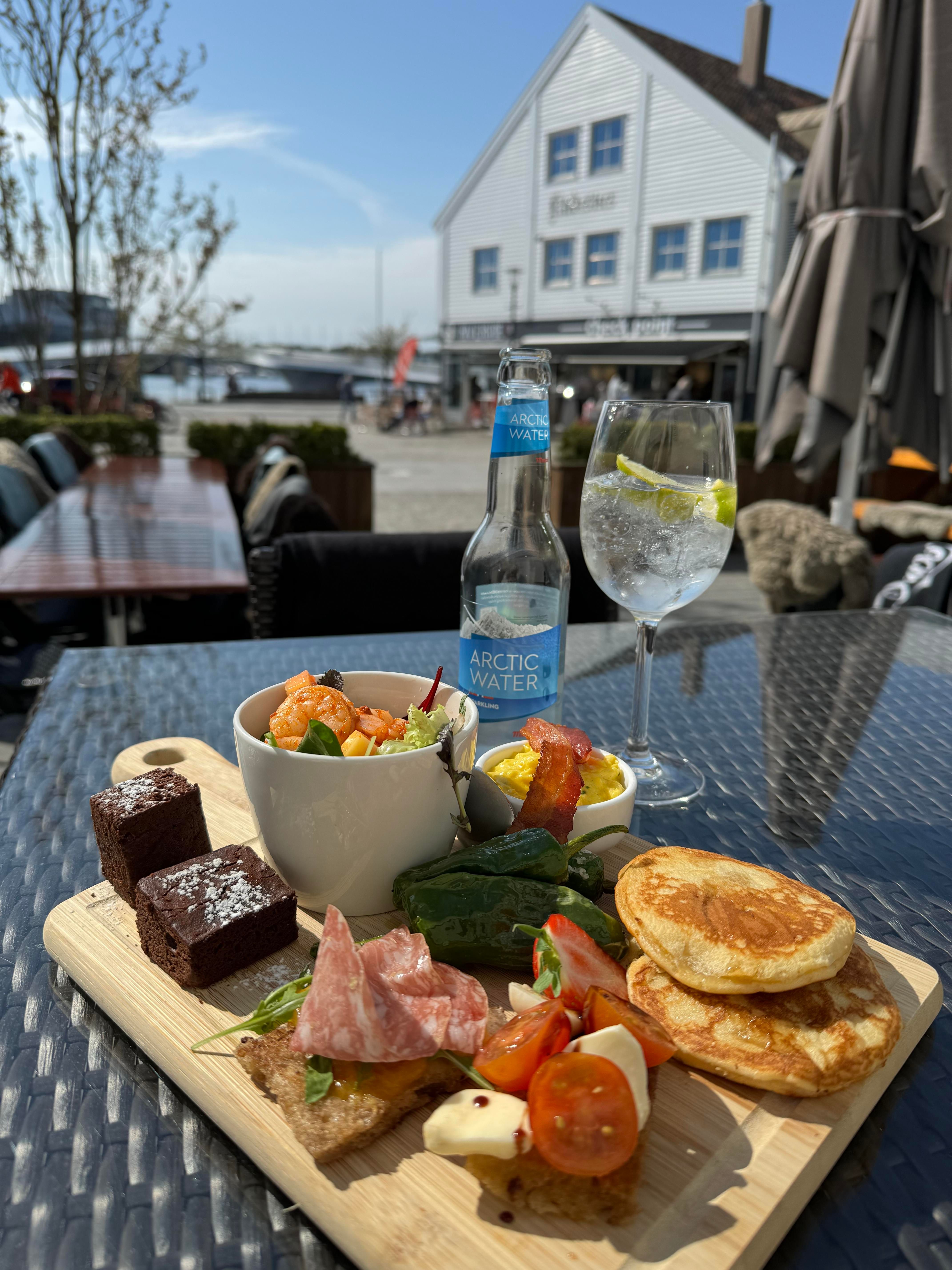 Food photo: tapas plate with a slice of cake, a small bowl of salad and scampi, a piece of bread with salami, a piece of bread with cheese and tomatoe