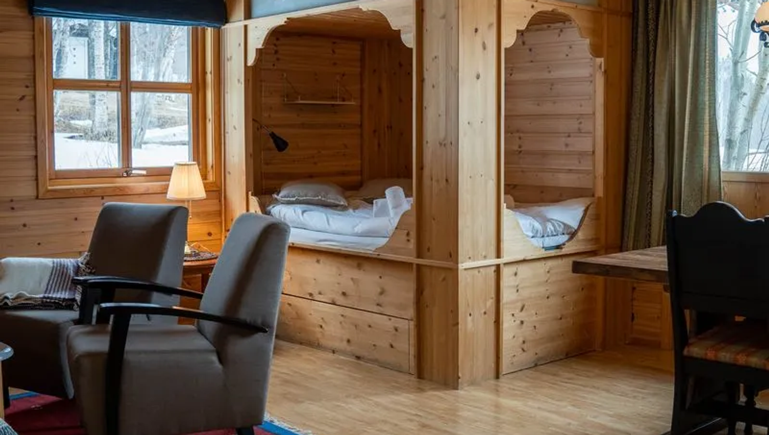 Cozy wooden cabin interior with twin beds, light, and seating area.