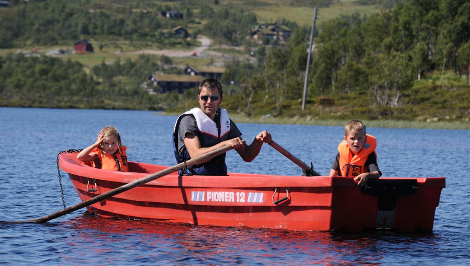 man in a rowing boat with 2 children