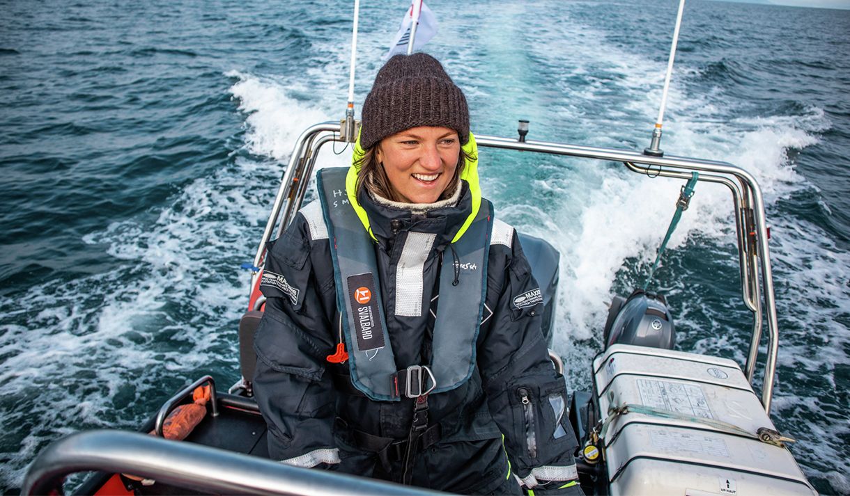 A smiling guide sailing a RIB boat across a fjord