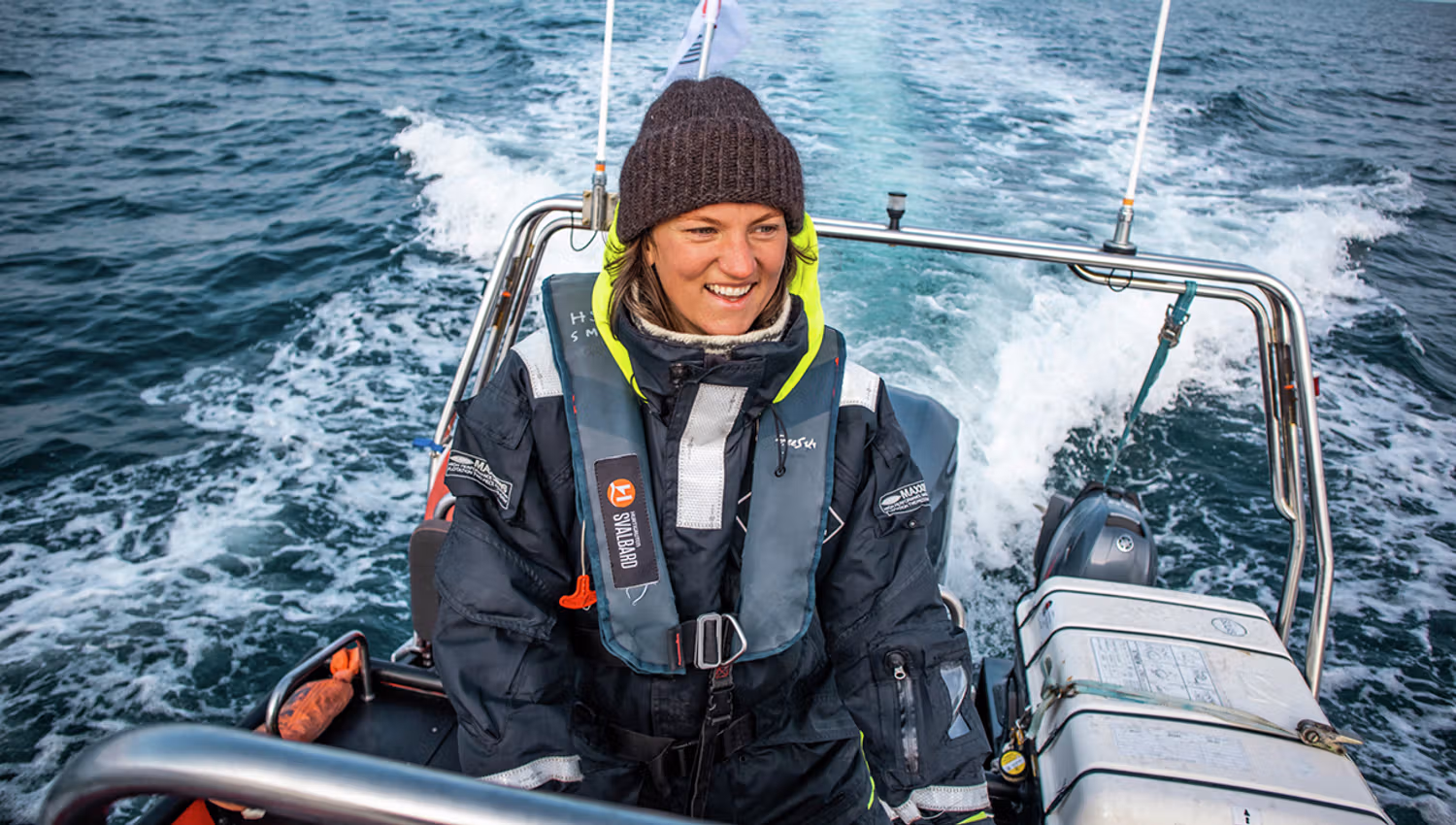 A smiling guide sailing a RIB boat across a fjord