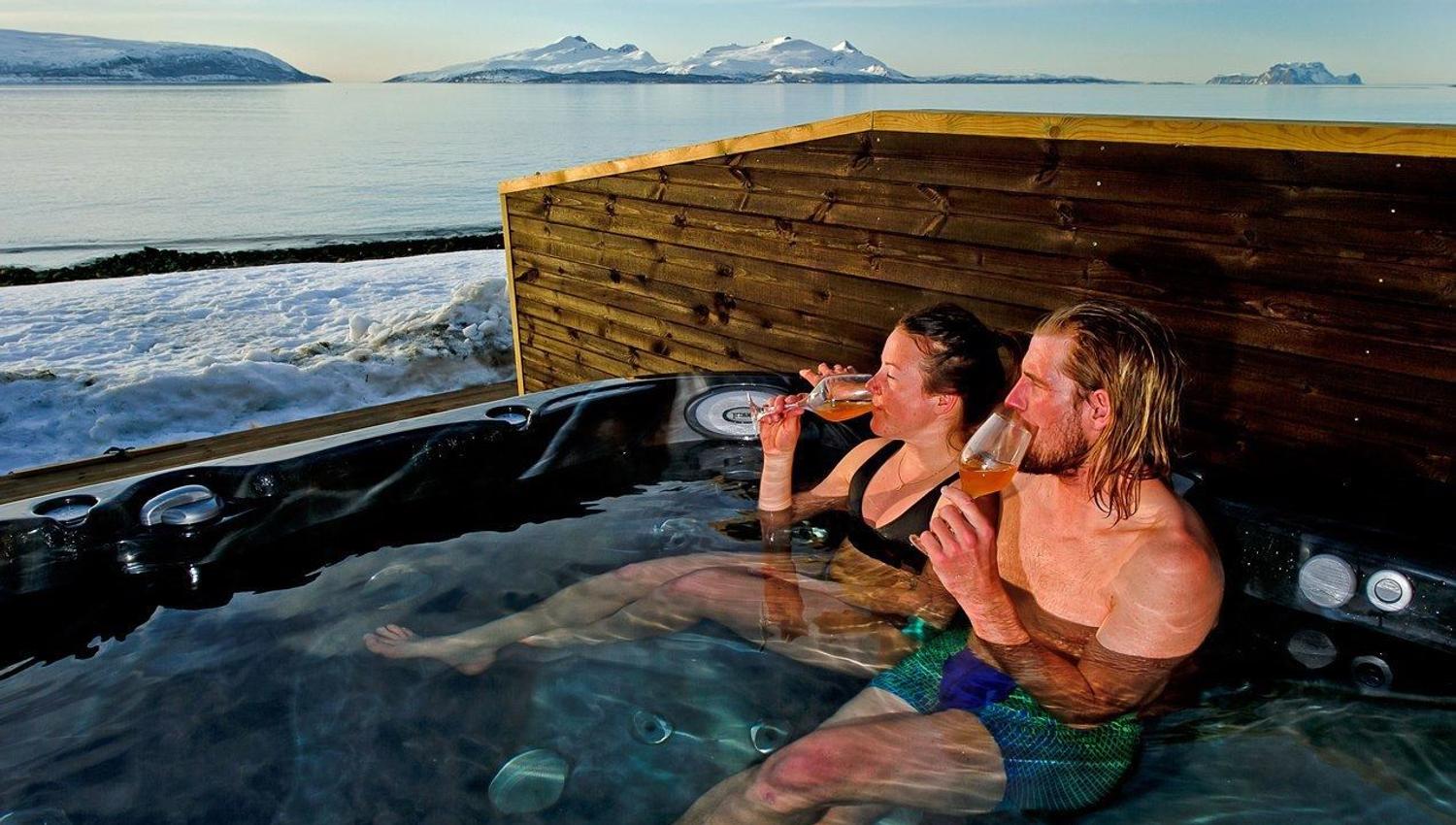 Two guests enjoying a drink in a jacuzzi outside