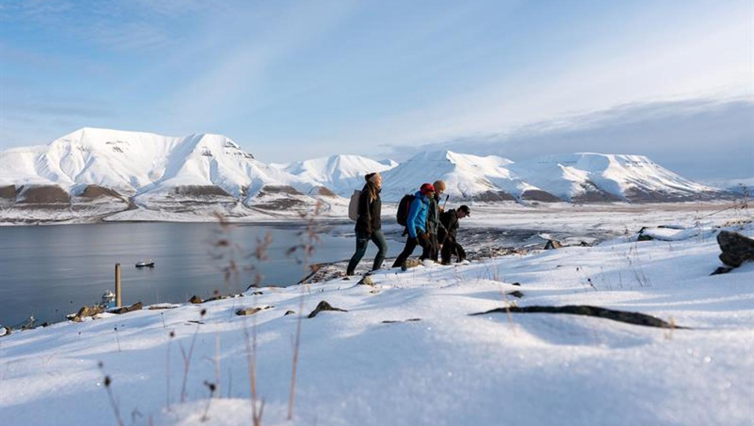 flere personer vandrer oppover fjellet i snødekt landskap