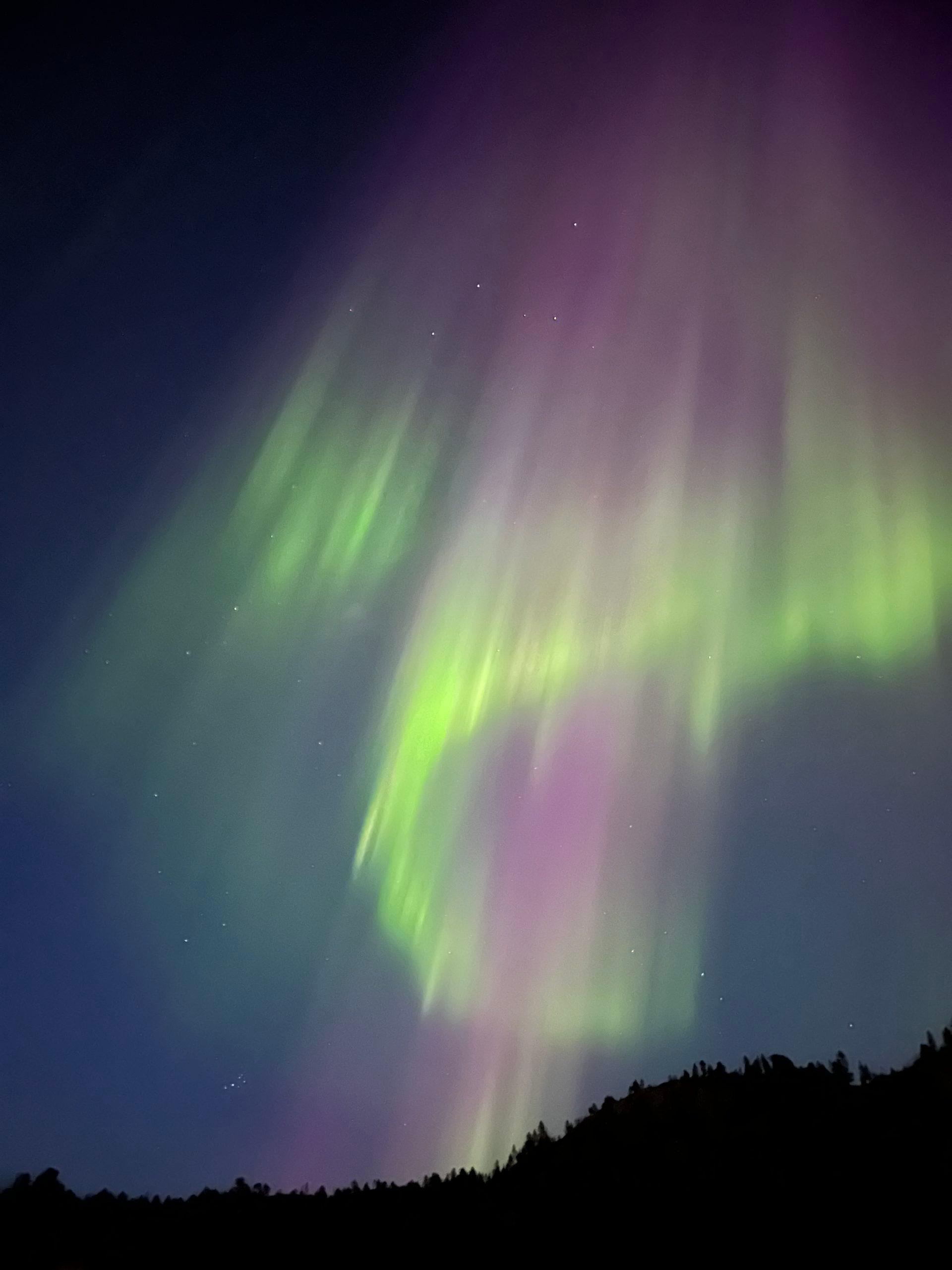 Aurores boréales colorées avec des teintes vertes et violettes dans le ciel nocturne.
