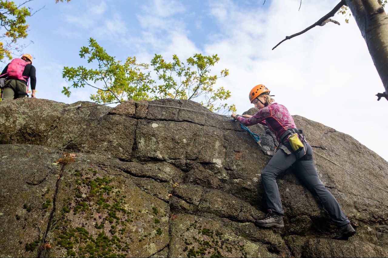En jente klatrer i Via Ferrata ruta og holder seg i fjellet