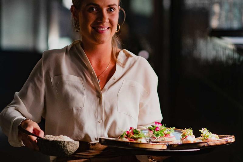 Female server carrying a tray of food