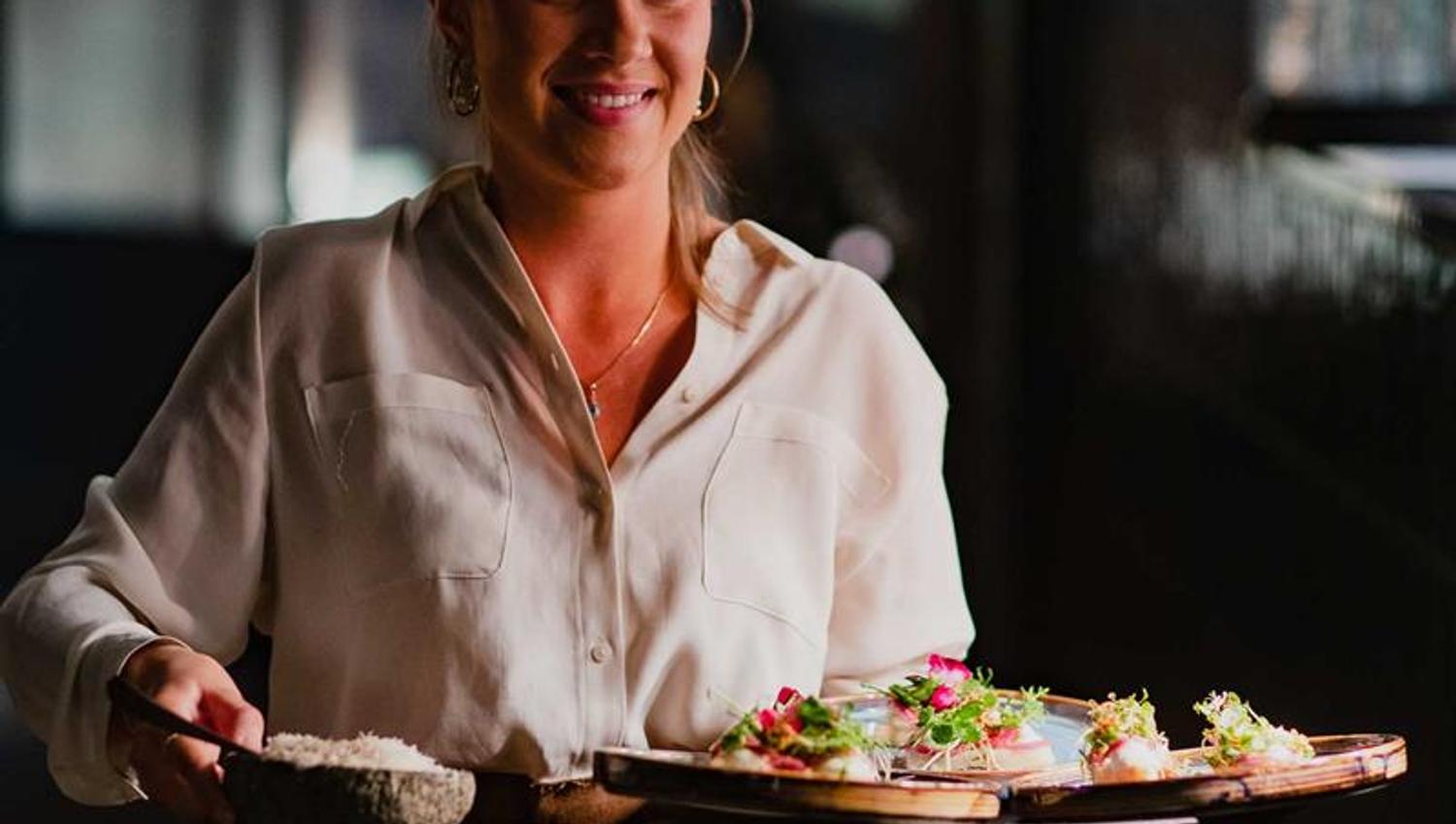 Female server carrying a tray of food