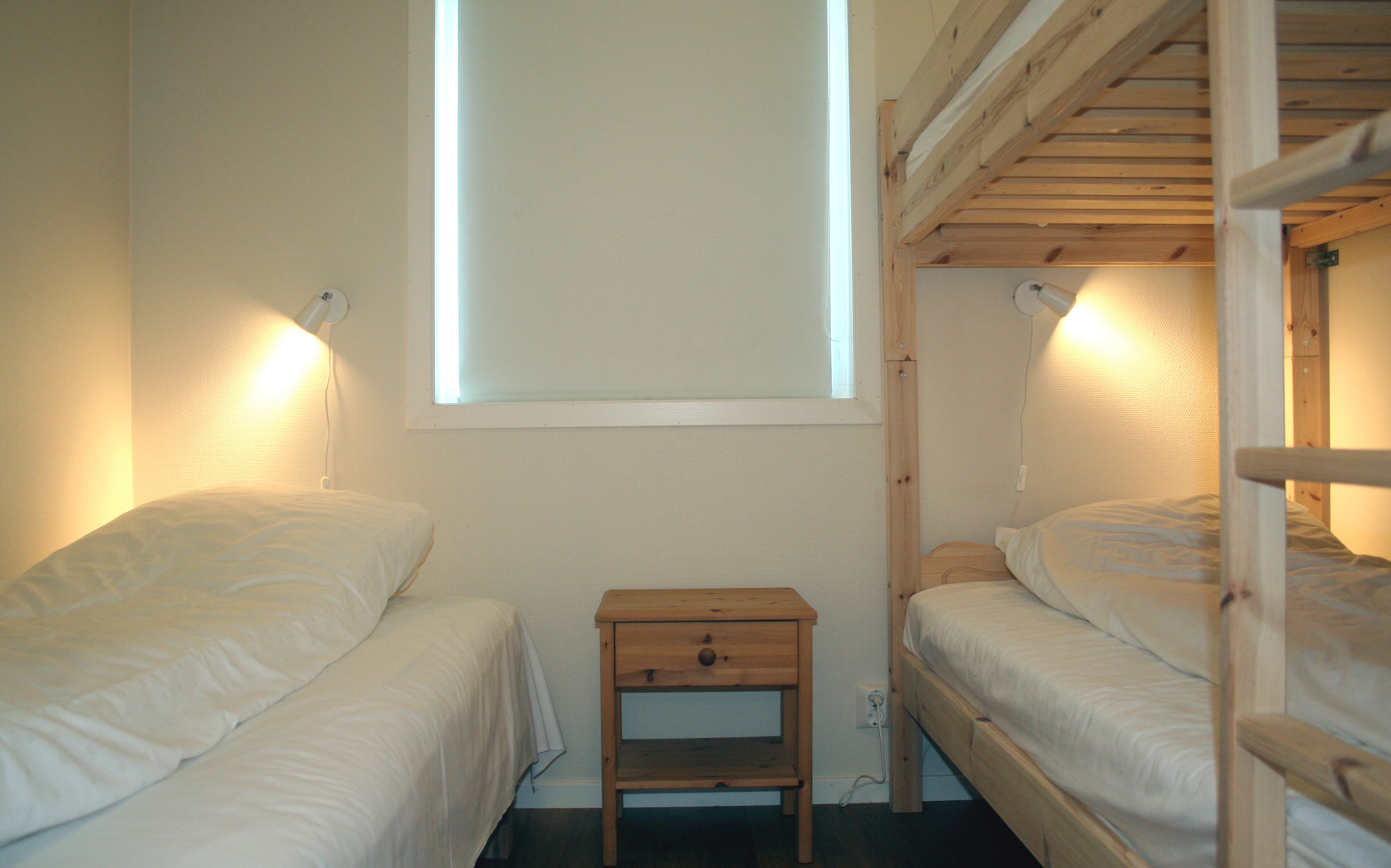 Family-friendly bedroom with single beds and bunk bed at Vågen Rom og Hytteutleige in Hardanger.