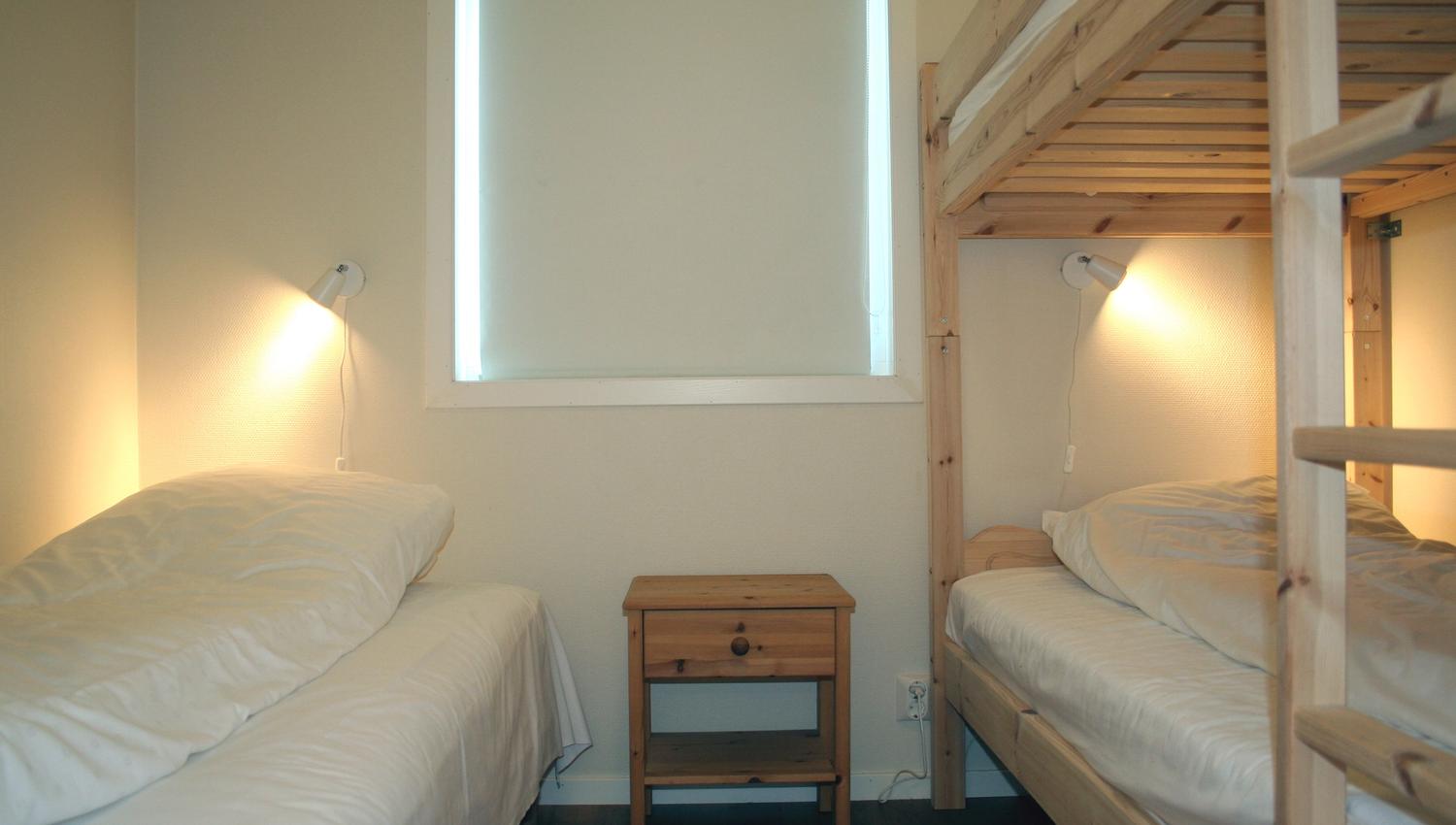Family-friendly bedroom with single beds and bunk bed at Vågen Rom og Hytteutleige in Hardanger.
