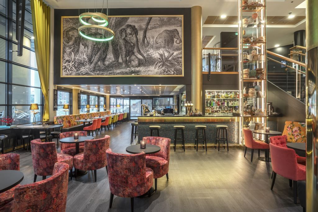 Glamorøs hotellbar med veggmaleriog gyldne detaljer.