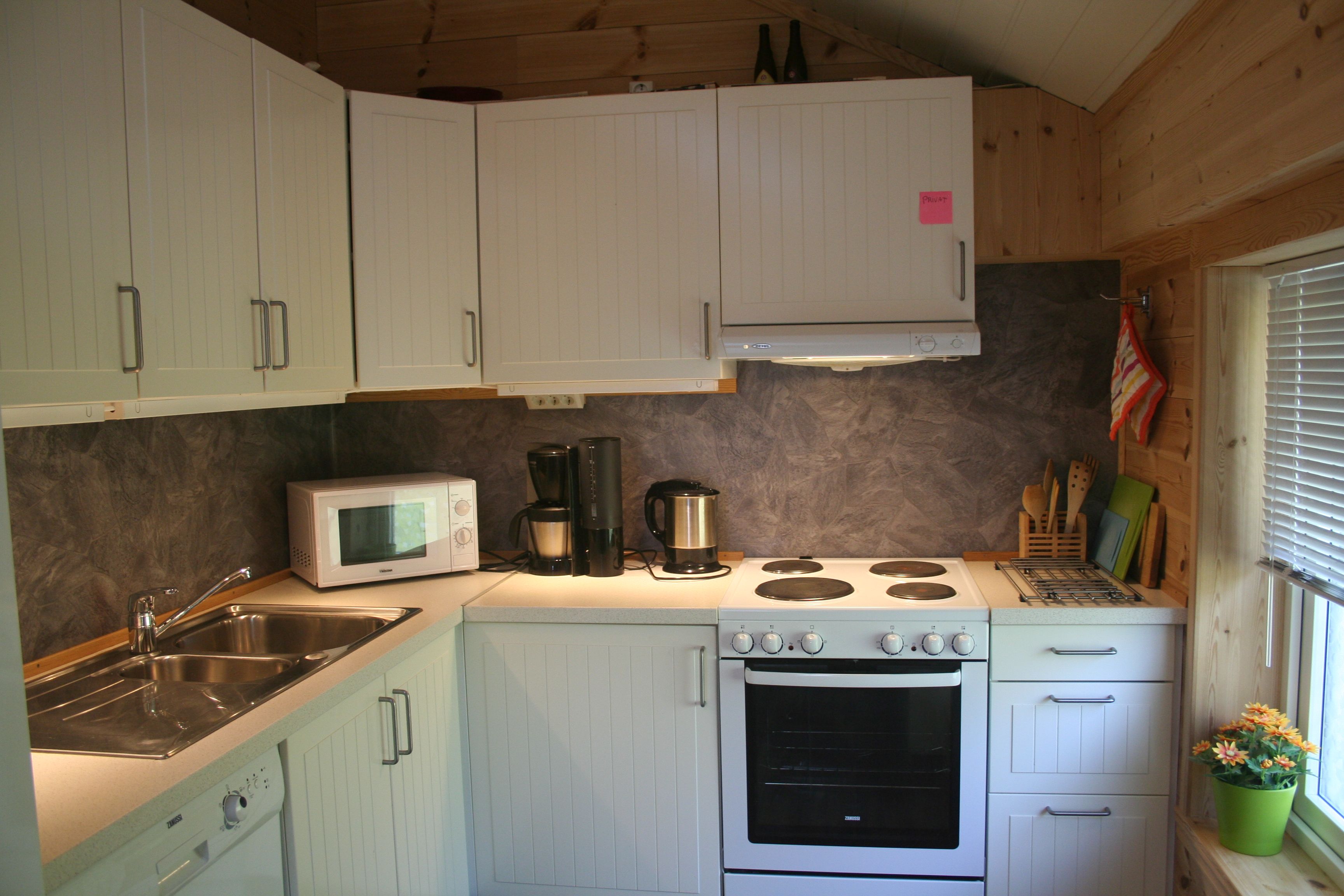 Fully equipped kitchen with stove, sink and white cabinets at Vågen Rooms and Cabins.