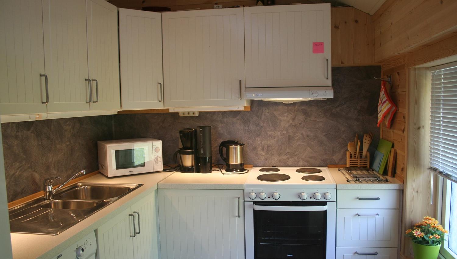 Fully equipped kitchen with stove, sink and white cabinets at Vågen Rooms and Cabins.