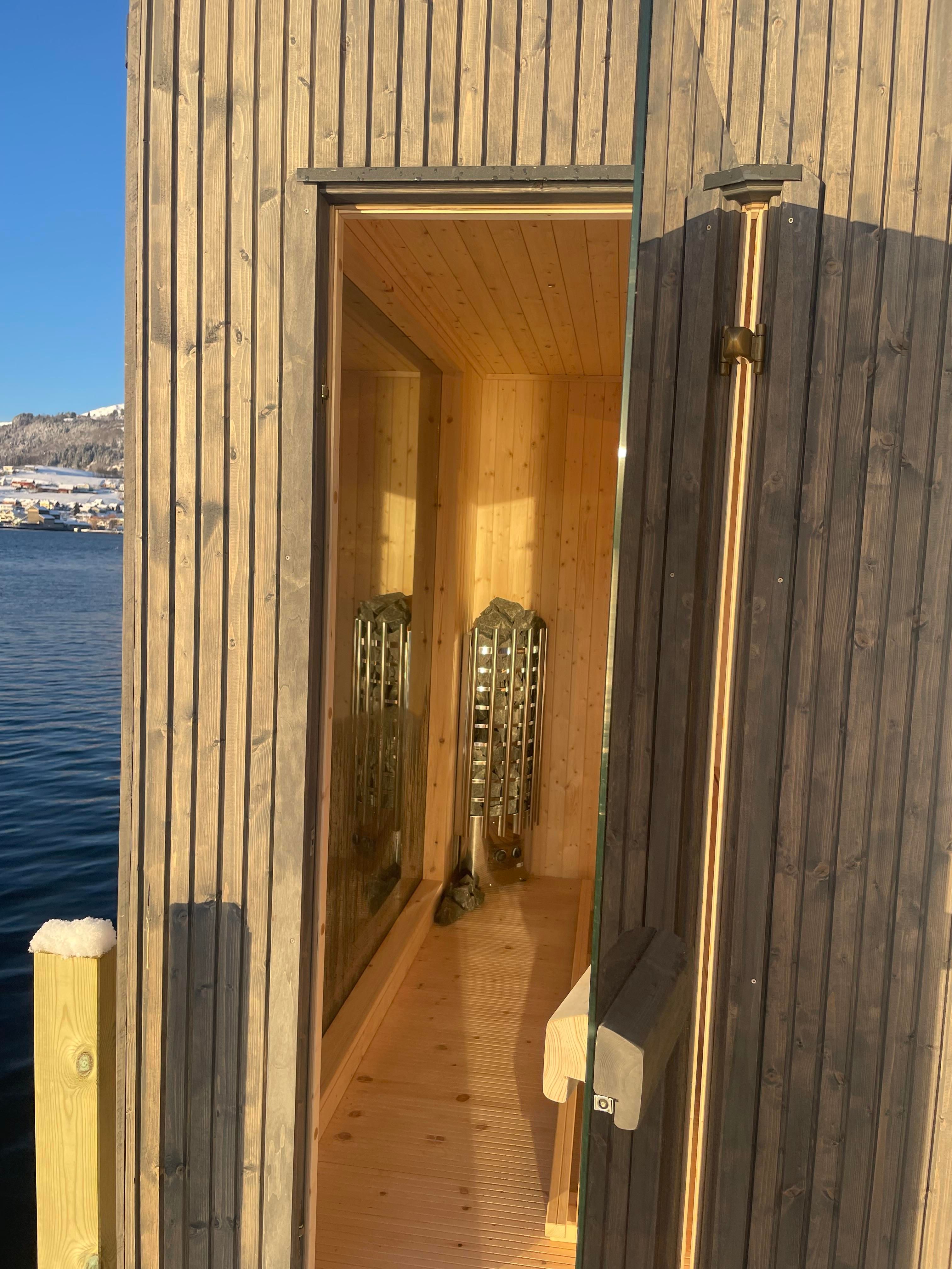 Exclusive fjordside sauna with large windows offering a unique nature experience.