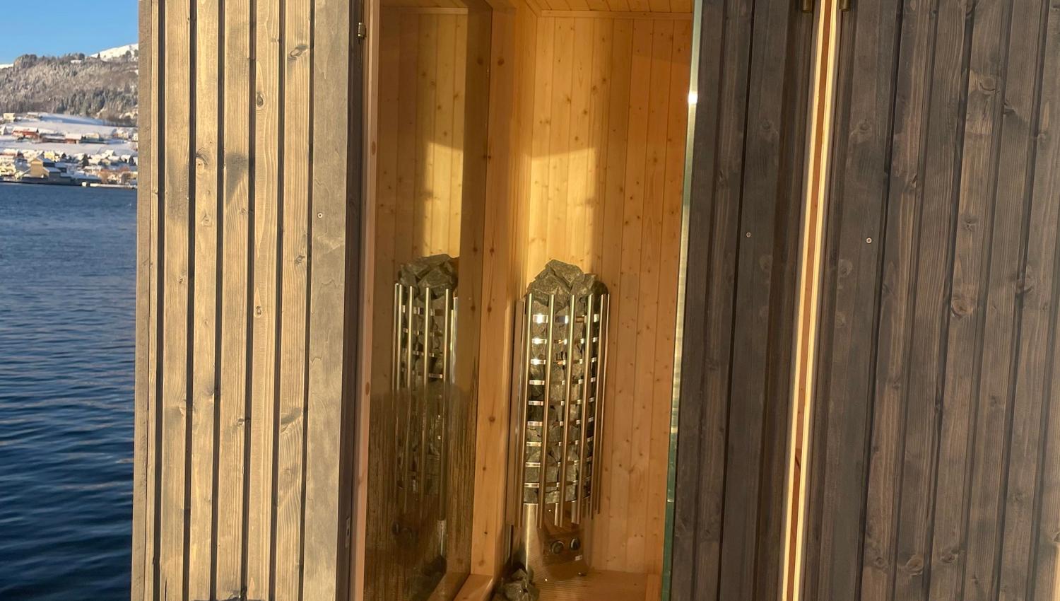 Exclusive fjordside sauna with large windows offering a unique nature experience.