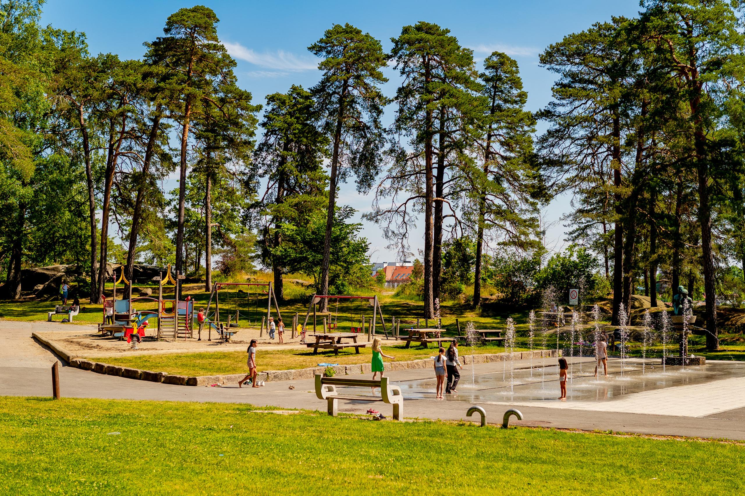 Children playing on playground equipment and in the water fountain in Kulåsparken