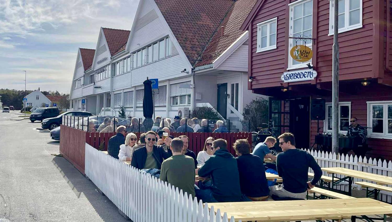Mennesker som koser seg på uteserveringen foran Sjøboden Pub i Mandal